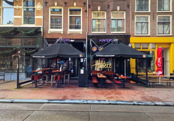 Interieur van Hunter’s Bar in Amsterdam, waar gasten genieten van drankjes en snacks terwijl ze live sportwedstrijden kijken in een gezellige sfeer.